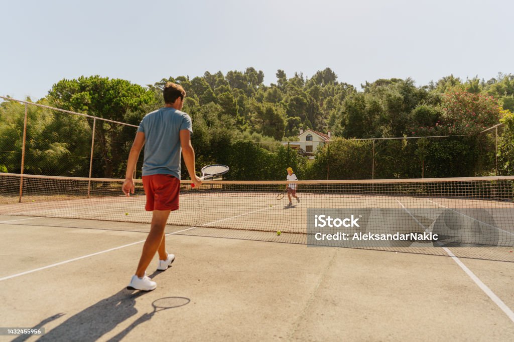 Practicing tennis with my dad Photo of a young boy and his father practicing tennis together 35-39 Years Stock Photo