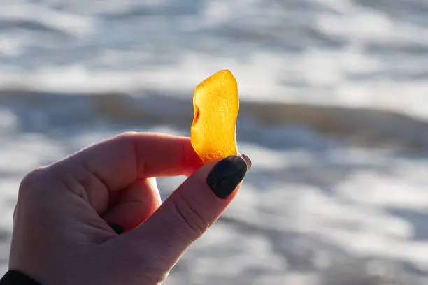 Photo of Beautiful big piece of yellow amber in the hand of a girl