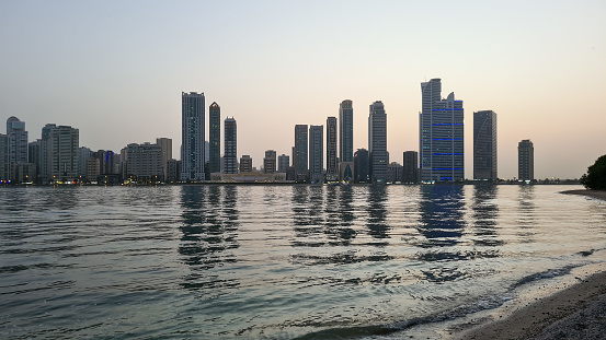 Sharjah, United Arab Emirates – August 4, 2022: Skyline of Sharjah with skyscrapers at the coastline.