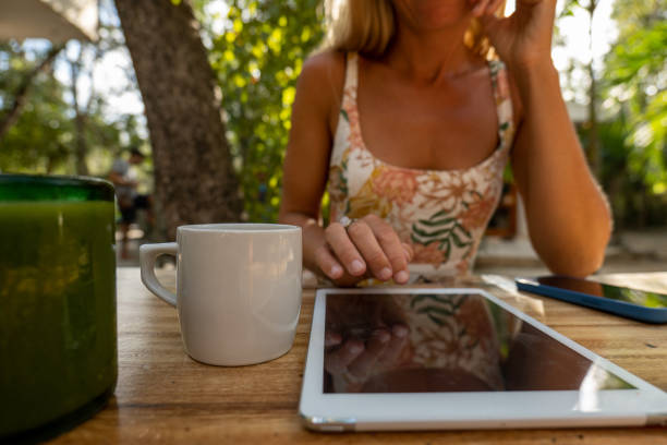 Woman using tablet computer by the pool, vertical screen mockup