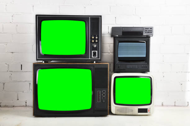 istock Four old vintage green screen televisions and a VCR stand against a white brick background. 1432460492