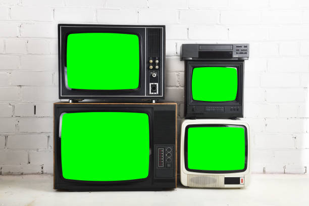 istock Four old vintage green screen televisions and a VCR stand against a white brick background. 1432460497