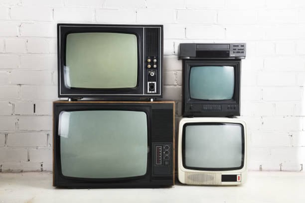 Four old vintage televisions with a VCR stand against a white brick background. Four old vintage televisions with a VCR stand against a white brick background. 1980 stock pictures, royalty-free photos & images