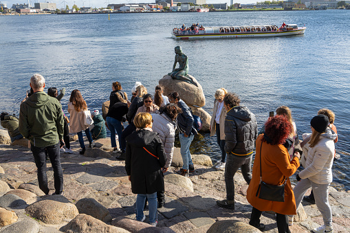 Copenhagen, Denmark. October 2022. a group of tourists taking pictures in front of the little mermaid statue in the city center