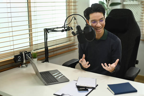 istock Man podcaster using laptop and microphone to recording podcast from home studio. Radio, podcasts and technology concept. 1432461734