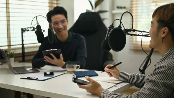 istock Smiling male radio host interviewing guest conversation while streaming podcast at home studio. 1432461739