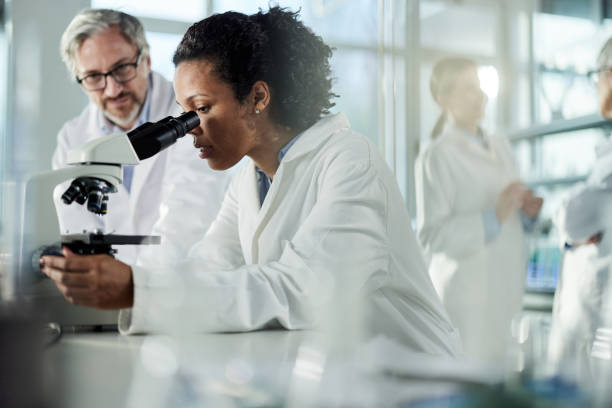 studente afroamericano di scienze che lavora al microscopio in laboratorio. - teamwork medical research science women foto e immagini stock