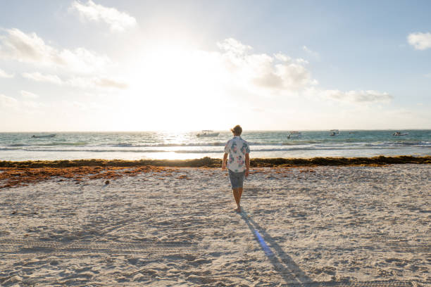 istock Young man walks on the beach at sunrise 1432462085