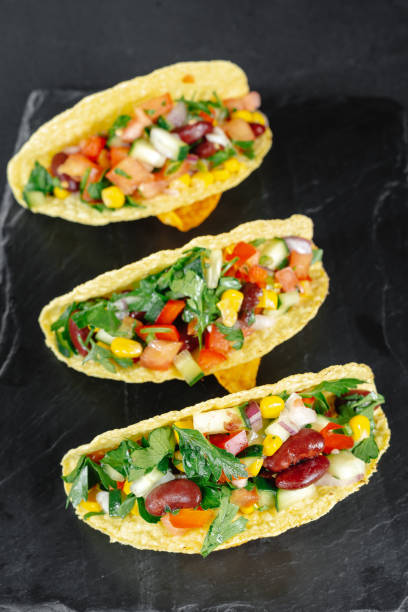 Mexican tacos with vegetables on a dark background on a slate. Reducetarian, flexitarian, pescatarian eating. Top view