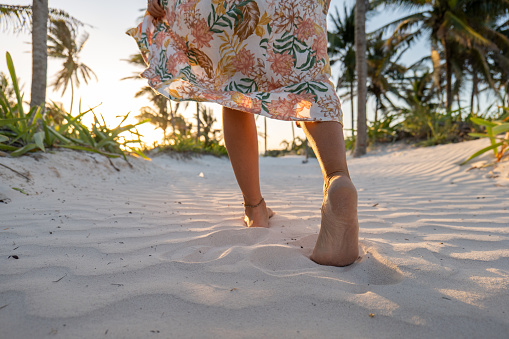 Feet of the man walking on the beach by the sea