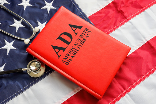 American flag, a book The Americans with Disabilities Act ADA law and stethoscope.