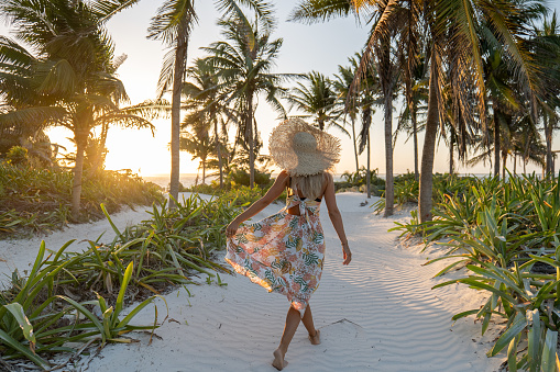 30's woman walks on a beautiful wild beach with palm trees in Mexico.