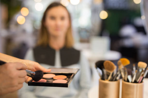 Hands of makeup artist holding tonal foundation palette and brush stock photo
