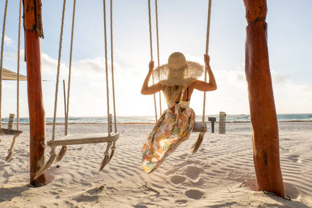 istock Young woman having fun swinging on the beach at sunrise 1432467155