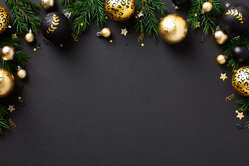 Merry Christmas greeting card template, frame, New Year banner design. Luxury gold baubles and fir branches on black background. Winter holidays composition. Flat lay, top view.