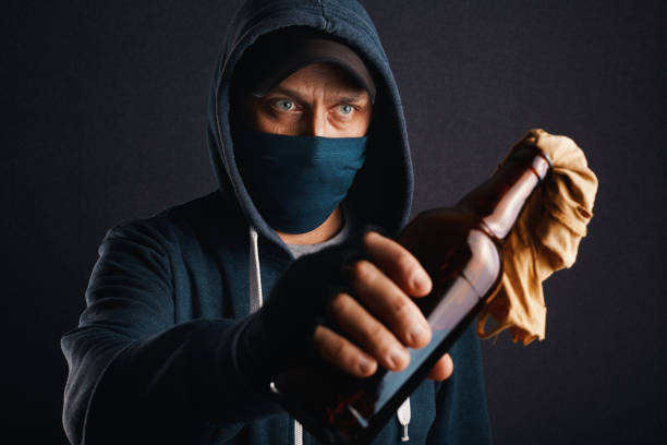 militant masculin, rebelle, anti-émeute portant un sweat à capuche, une casquette et un masque facial tenant une bouteille à moitié pleine de liquide inflammable connu sous le nom de cocktail molotov prêt à être jeté. manifestation de rue violente  - extremism photos et images de collection