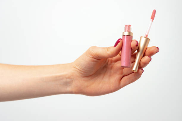 istock Female hand holding lipgloss against light gray background 1432470802