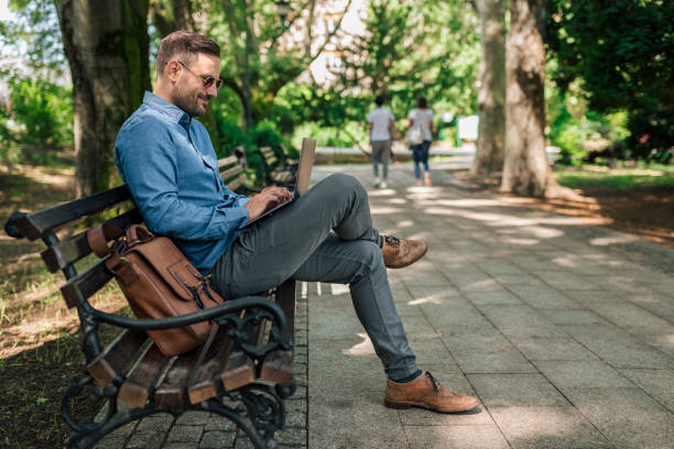istock Joyful entrepreneur or businessman, sending an e-mail from the park bench. 1432470829