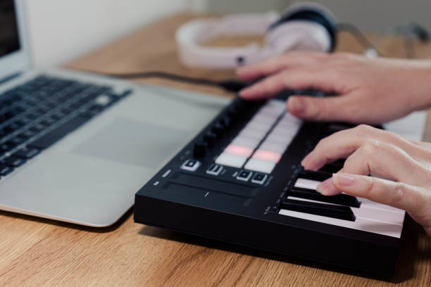 istock Midi Keyboard musician playing midi keyboard for arranging music on laptop computer Music production technology concept 1432473571