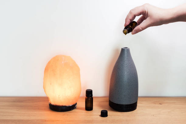 istock Salt lamp with essential oils and aroma oil diffuser hand pouring in essential oil 1432473574