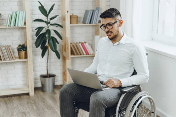istock Businessman sitting in wheelchair and using laptop 1432474075