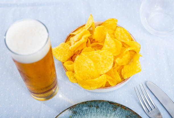 Appetizing snack of potato chips with a glass of foamy beer. Close-up image