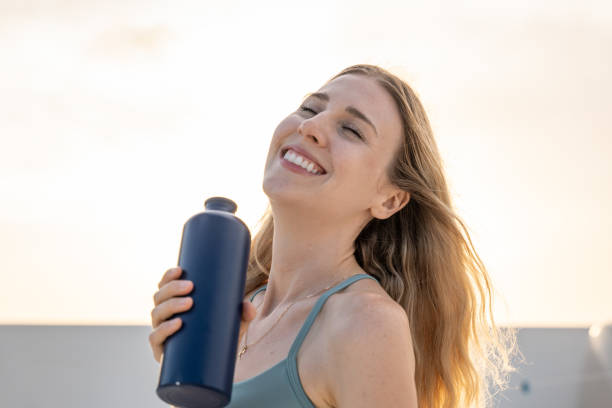 Portrait of young woman drinking water from reusable bottle stock photo