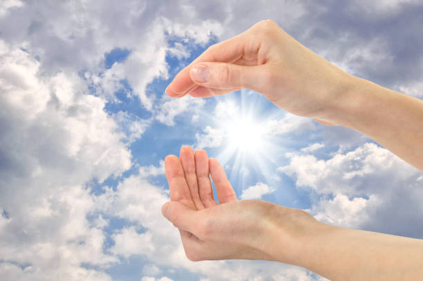 istock Human hands on a background of solar cloudy sky 1432477694