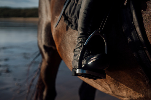 Close up of a womans boot sitting in a stiruup while she is  horseback riding at the beach in the North East of England.