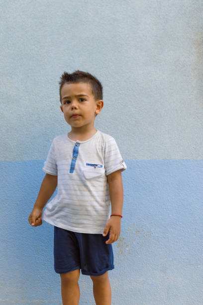 Portrait of a cute little boy against blue wall background