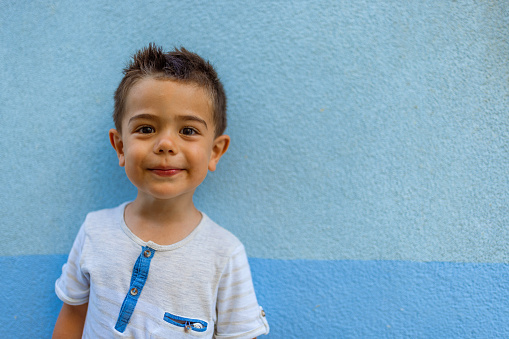 Portrait of a cute little boy against blue wall background