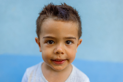 Portrait of a cute little boy against blue wall background