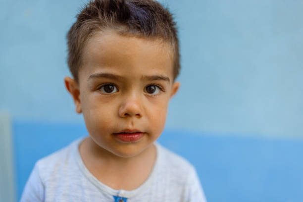Portrait of a cute little boy against blue wall background