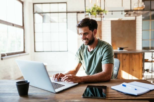Smiling young man working or studying from home stock photo