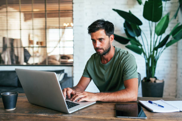 istock Serious young man studying from home, typing on laptop 1432483301