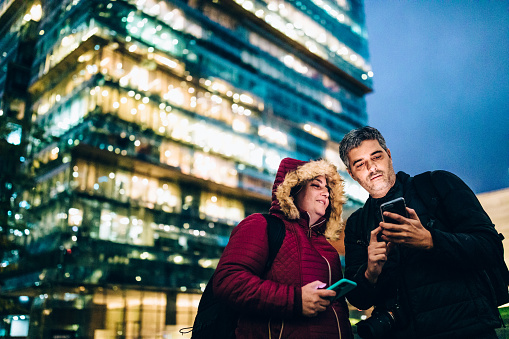 Couple using cell phone in the city of Santiago at night