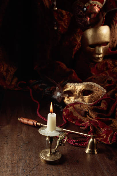 istock Burning candle in an old brass candlestick and carnival masks. 1432484727