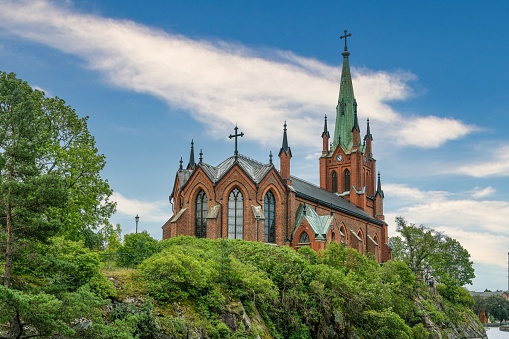 , Sweden: A low-angle view of the beautiful Trollhattan church parish surrounded by green trees in Trollhattan, Sweden