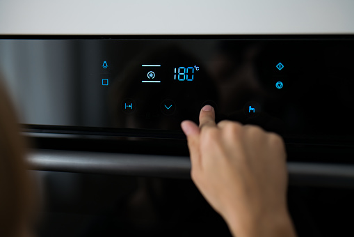 a child presses a button on the touch screen of a modern electric oven. touch display microwave oven