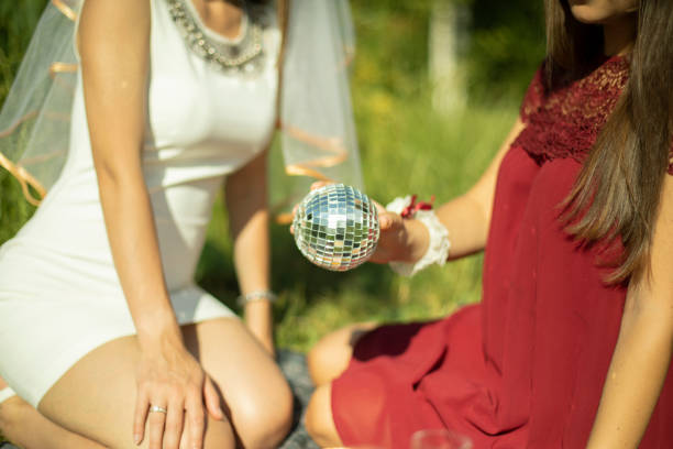 les filles en été en robe s’assoient sur l’herbe. la fille tient la balle dans sa main. boule miroir dans la paume de votre main. - imagination fantasy invisible women photos et images de collection