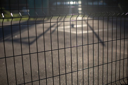 Fence on sports ground in sunlight. Stadium details. Sports ground in morning. Dawn in city in detail.