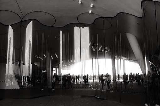 Hamburg, Germany: The grayscale view of people reflection on the curved wavy mirror facade on Elbphilharmonie