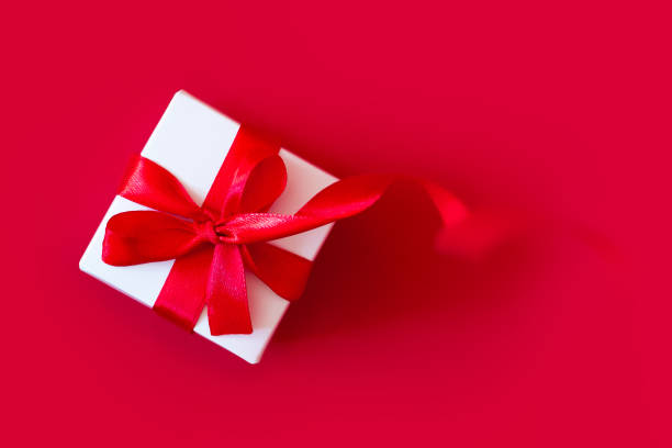 istock White box with a red ribbon on a red background, top view, copy space. Greeting card concept 1432492146