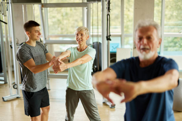 istock Senior couple doing stretching exercises with personal trainer at the gym 1432492259