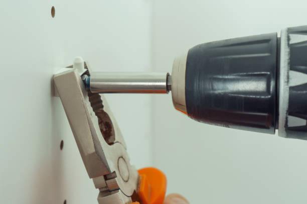 istock Closeup of screw to insert plastic support, assembling dresser or wardrobe. Holding screwdriver with pliers. 1432493939