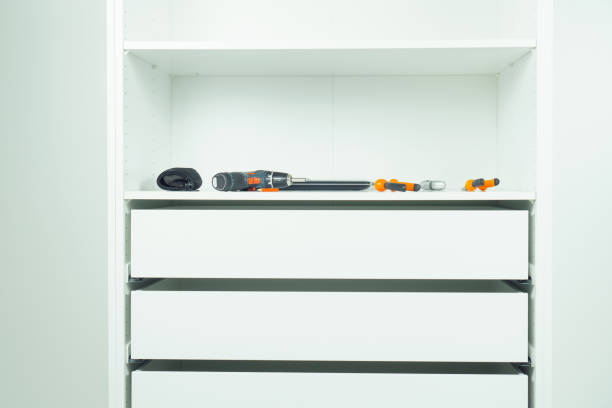 istock Inserted and fixed cabinet drawers and shelves. Assembling white dresser or wardrobe. Screwdriver, pliers, knife, pencil 1432493945