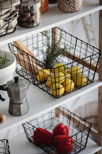 Vertical shot of modern kitchen shelf with various food ingredients, vegetables and lemons on white background