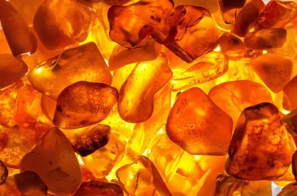 Photo of Closeup shot of a heap of amber stones with backlight background