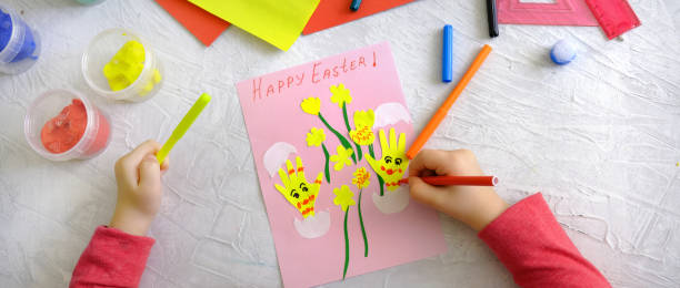 istock Child creating card with Easter funny eggs and flowers from colorful paper. Handmade. Project of children's creativity, handicrafts, crafts for kids. Happy easter text 1432500105