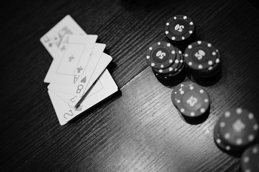 A greyscale shot of a poker chips and cards on the table